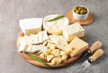 جبن القريش جبن القريش جبن طازج له نكهة خفيفة وحامضية قليلا، وتحتوي 100 غرام من الجبن القريش على حوالي 17 غراما من البروتين، وهي حوالي ضعف ونصف الكمية الموجودة في بيضة واحدة، و3 أضعاف تلك الموجودة في الزبادي الكامل الدسم. ويعتبر جبن القريش منخفض السعرات الحرارية مقارنة بالأجبان الأخرى. وتحتوي 100 غرام من الجبن القريش على 111 سعرة حرارية، بينما تحتوي الكمية ذاتها من جبن الشيدر على 416 سعرة حرارية. الجبن الأزرق غنيّ بالدهون المشبعة والملح وقليل البروتين (غيتي) الأجبان اليونانية: الفيتا والحلوم الأجبان المملحة مثل الفيتا والحلوم غنية بالبروتين، لكنها من بين أكثر أنواع الأجبان ملوحة، لذا يفضل تناولها باعتدال، كما يقول هوبسون. وعلى الرغم من أن الفيتا لا تزال أكثر ملوحة، إلا أنها أقل سعرات حرارية من العديد من الأجبان الصلبة، مما يجعلها خيارا جيدا لمن يهتمون بوزنهم. كما أنها تصنع تقليديا من حليب الأغنام أو الماعز، الذي يحتوي على فيتامينات ومعادن أكثر من حليب البقر في الحصة الواحدة. وحليب الأغنام غني بشكل خاص بالكالسيوم والمغنيسيوم والزنك وفيتامينات إيه وبي 2 وبي 12 وفيتامين د، مما يساعد على تقوية جهاز المناعة ودعم صحة العظام. الجبن الأزرق قال هوبسون عن الجبن الأزرق إنه "غنيّ ولاذع، مع بكتيريا العفن الحية التي قد تفيد بكتيريا الأمعاء. لكنه غنيّ أيضا بالدهون المشبعة والملح وقليل البروتين". ووجد أن جبن الروكفور الفرنسي، المعروف بعفنه وعروقه الزرقاء، يتمتع بخصائص مضادة للالتهابات. وهذا قد يقدّم أدلة على ما يسمى "المفارقة الفرنسية" حيث يتمتع سكانها بصحة جيدة رغم اتباعهم نظاما غذائيا غنيا بالدهون المشبعة.